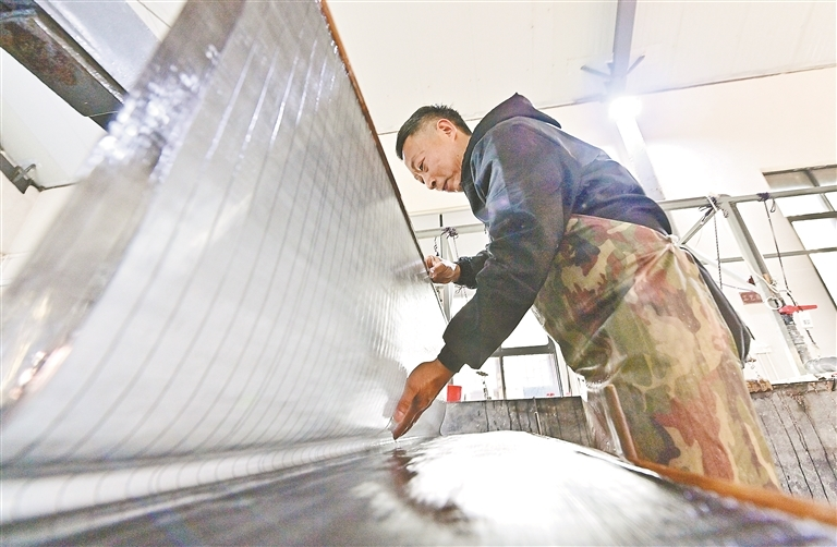 A Qianshan paper maker lifts a wet sheet from the vat