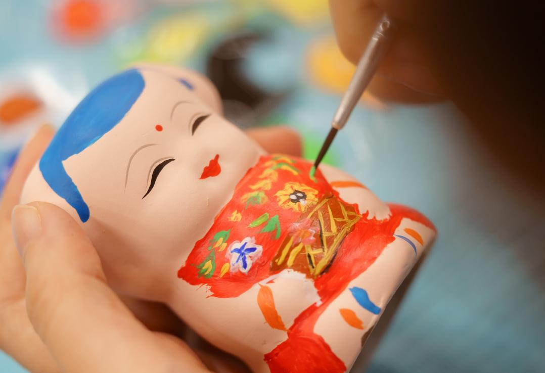 A fine brush adding colour to a Huishan A Fu figure