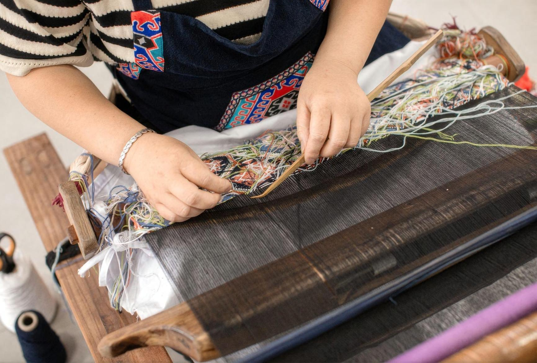 Hands working the threads on a Tujia brocade loom
