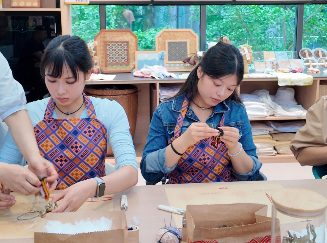 Visitors sewing brocade sachets with guidance